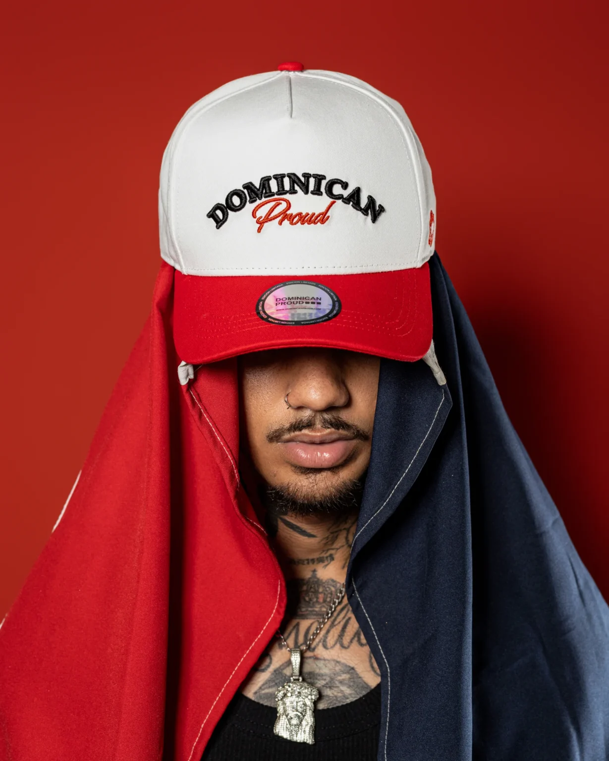 Modelo luciendo gorras Dominican Proud apiladas sobre fondo rojo